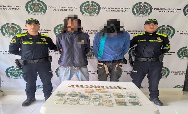 Dos capturados y dos policías uno a la derecha y otro a la izquierda de ellos