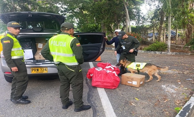 Tres policías, un ciudadano y un guía canino realizando registro un vehículo 
