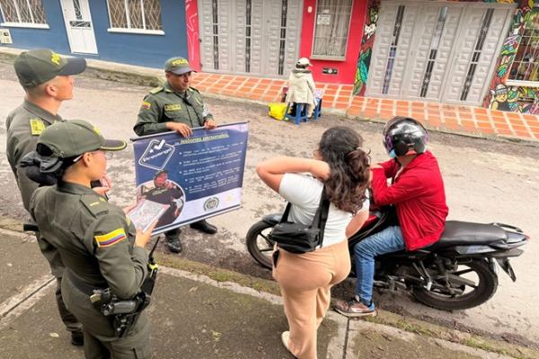 Tres policías haciendo camañas de prevención frente a una persona en su motocicleta y una ciudadana 