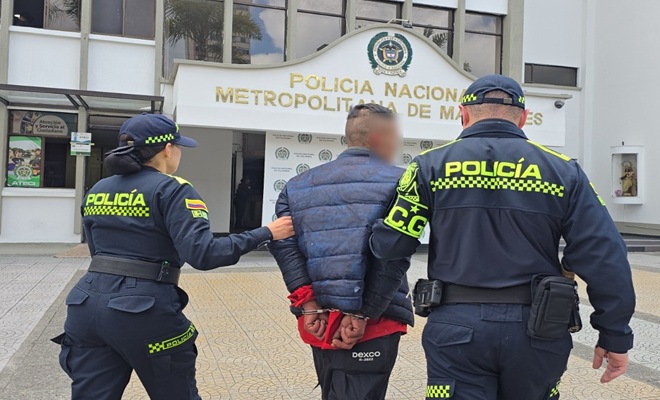 Dos policías y un capturado de espaldas 
