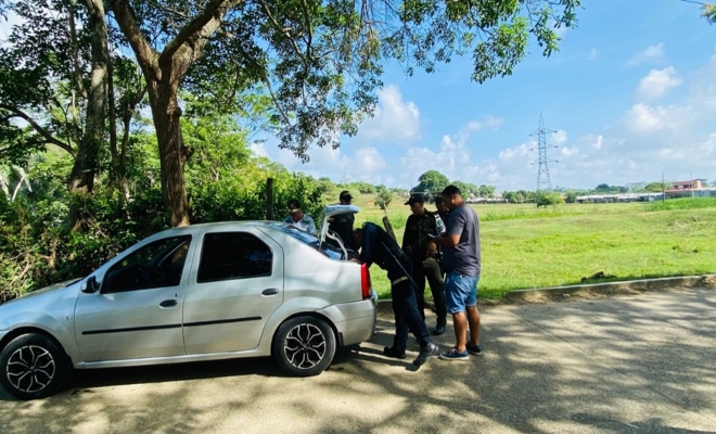 un policia registrando un carro un ciudadano observando y un policia prestando seguridad 