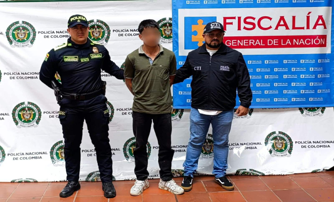 Un hombre capturado en medio de un polic&iacute;a y un funcionario de la fiscal&iacute;a.