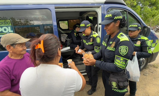 Tres funcionarias policiales entregando chocolate a la comunidad