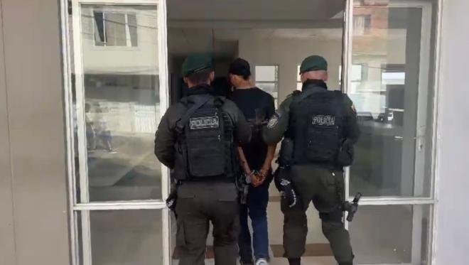 Hombre capturado de camiseta negra en medio de dos policías