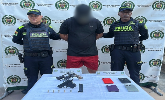 Dos policías, un capturado, encima de una mesa elementos incautados 