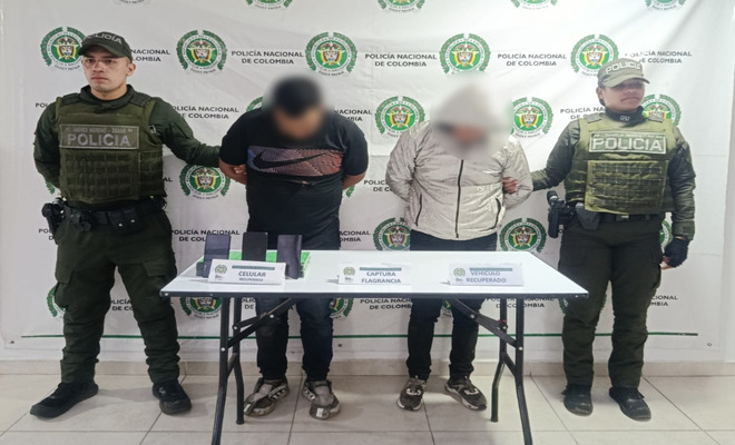 Dos personas capturadas esposadas con dos policías en cada lado 