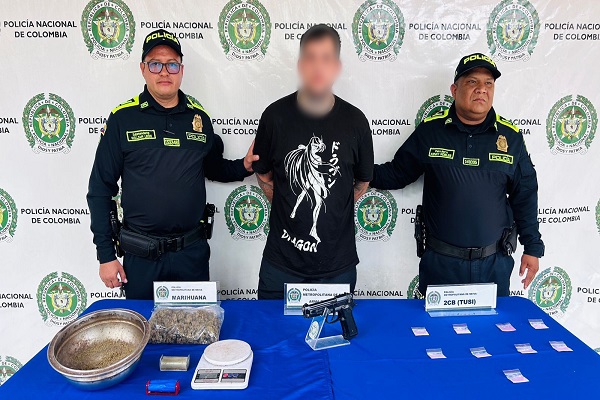 Dos Policías, una persona capturada, mesa con arma de fuego, estupefacientes