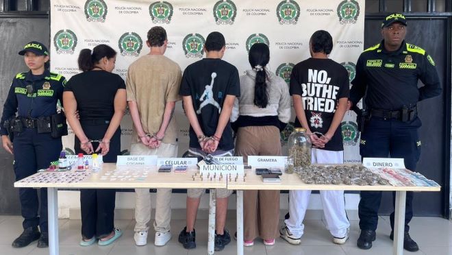 Dos policías al lado de cinco capturados con elementos