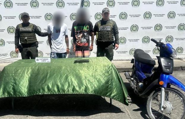 Dos policías al lado de dos hombres capturados por hurto