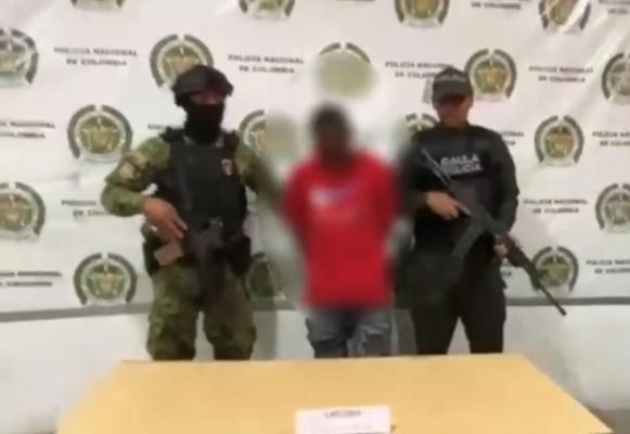 Dos policías al lado de un hombre capturado