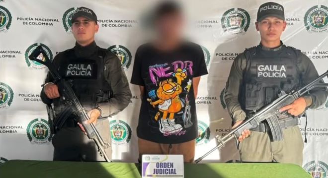 dos polic&iacute;as al lado de un hombre capturado por orden judicial 