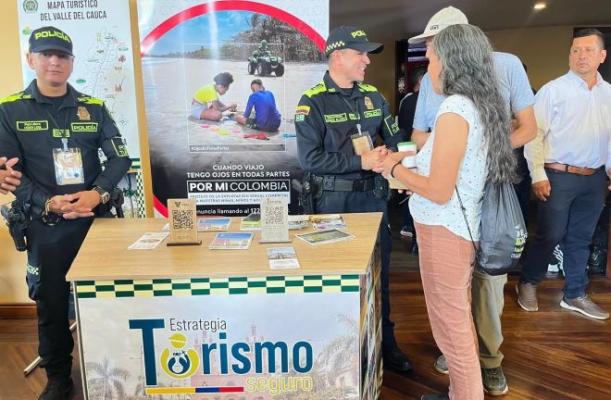 Dos policías en puesto de información de turismo con turistas