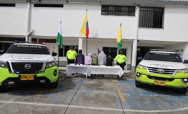 Miembros de la SIJIN custodia personas capturadas en la mesa elementos incautados  y a los dos costados dos vehículos uniformados