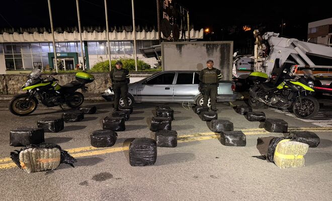 Dos policías con paquetes de marihuana incautada