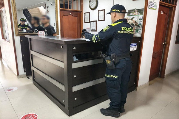 Policía con ciudadanos realizando verificación a la documentación en el sector hotelero
