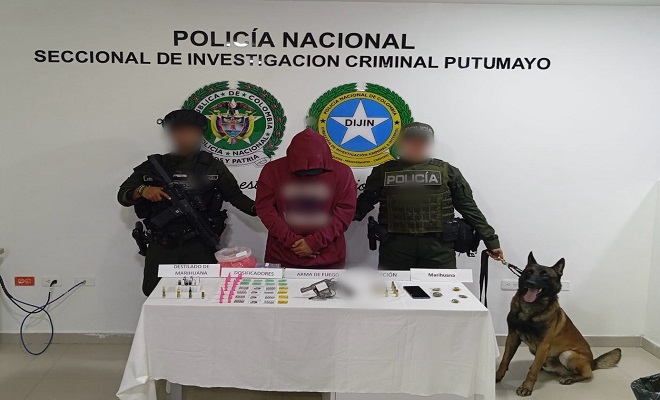 Dos polic&iacute;as, un canino frente a un capturado y elementos con estupefacientes sobre una mesa incautados
