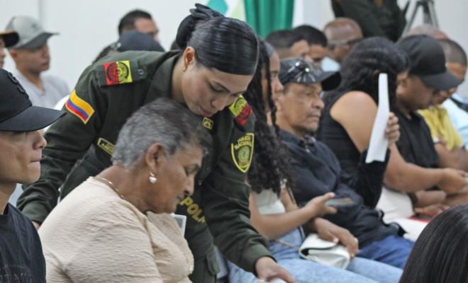 Auxiliar de Policía orienta a una ciudadana sobre cómo diligenciar el formato de preguntas durante la audiencia pública de rendición de cuentas.