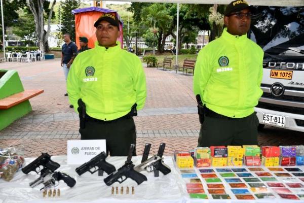 Dos policías encima de una mesa material incautado